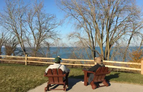 two people sit on adirondack chairs overlooking Lake Michigan