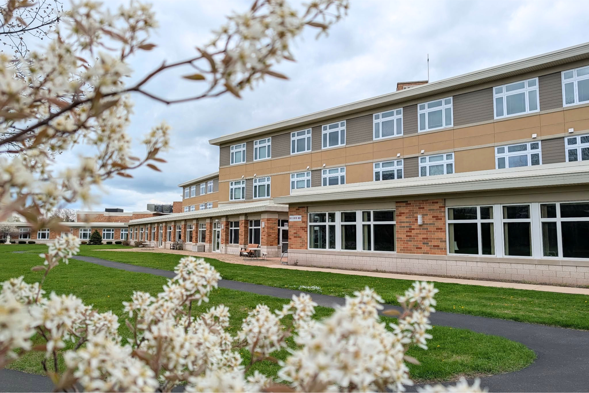 Siena Retreat Center building in Racine Wisconsin with flowering trees framing the photo
